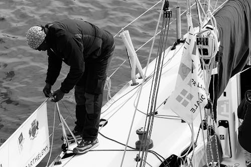 бесплатная мужчина в черно сером пиджаке на перилах лодки Стоковое фото
