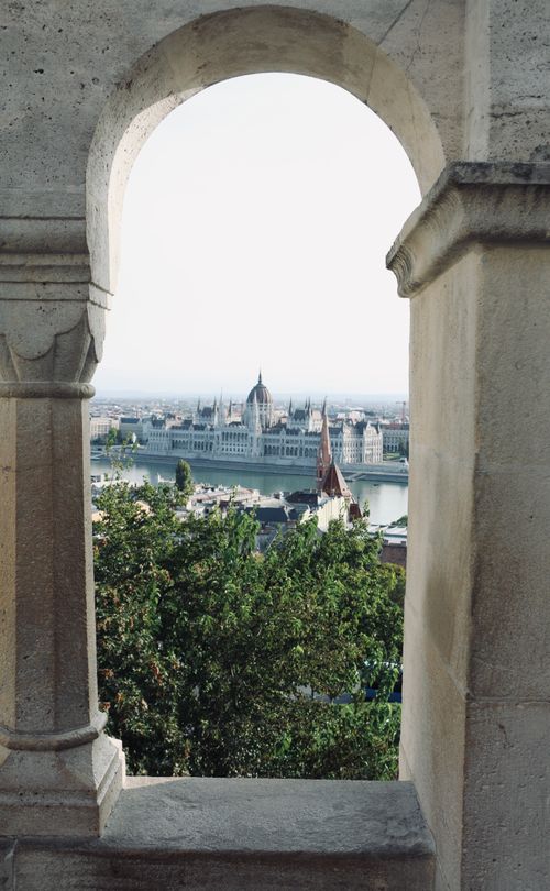 Free Scenic view of the Hungarian Parliament through an arch at Fisherman's Bastion in Budapest. Stock Photo