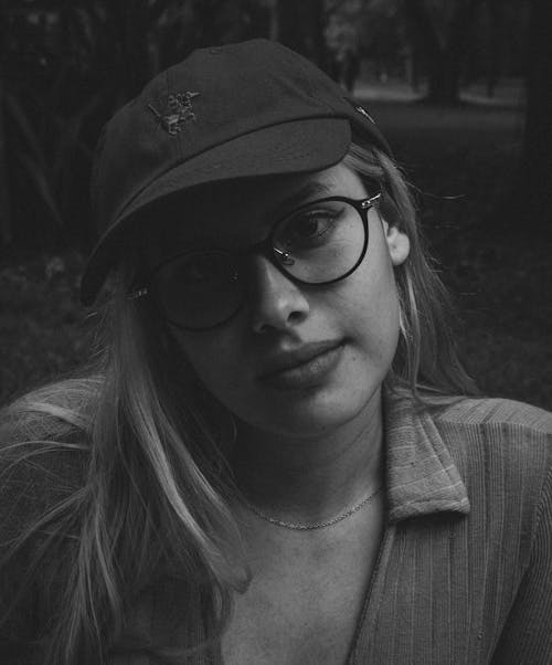 Black and White Photo of a Young Woman Wearing Eyeglasses and a Cap 