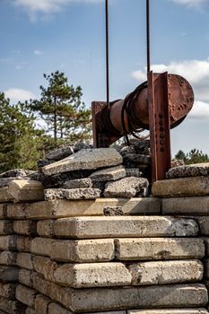 Stacked stone blocks with industrial crane against blue sky, depicting construction progress.