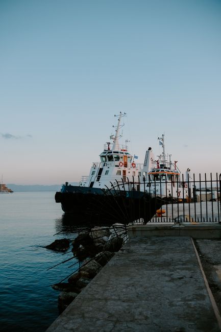 Calm harbor scene with two docked ships viewed at dawn, offering serene maritime charm.