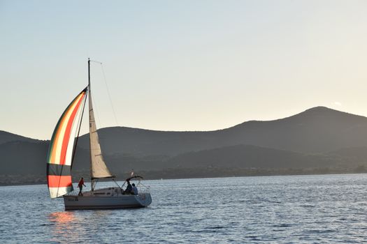 Serene sunset sailing scene with a colorful sailboat on Croatian waters.