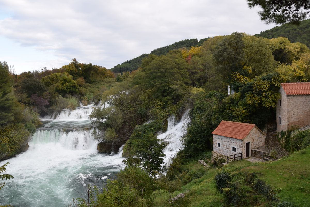 Stone house surrounded by waterfalls and lush greenery at Krka National Park