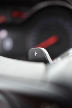 Close-up of a modern car's gear shift lever with a plus symbol, emphasizing sleek interior design.