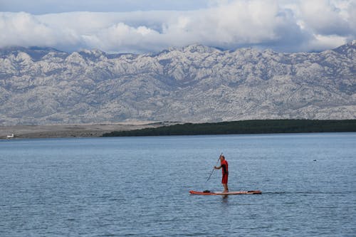 Man Paddleboarding on a Lake in front of Mountains