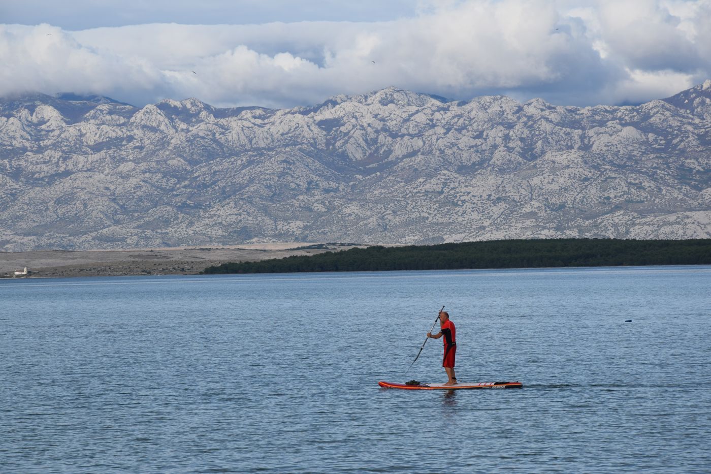 Paddler standing on a paddleboard on a calm mountain lake during a recreational water outing