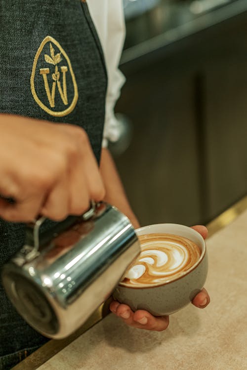 Free Barista Pouring Milk in Coffee in Cup Stock Photo