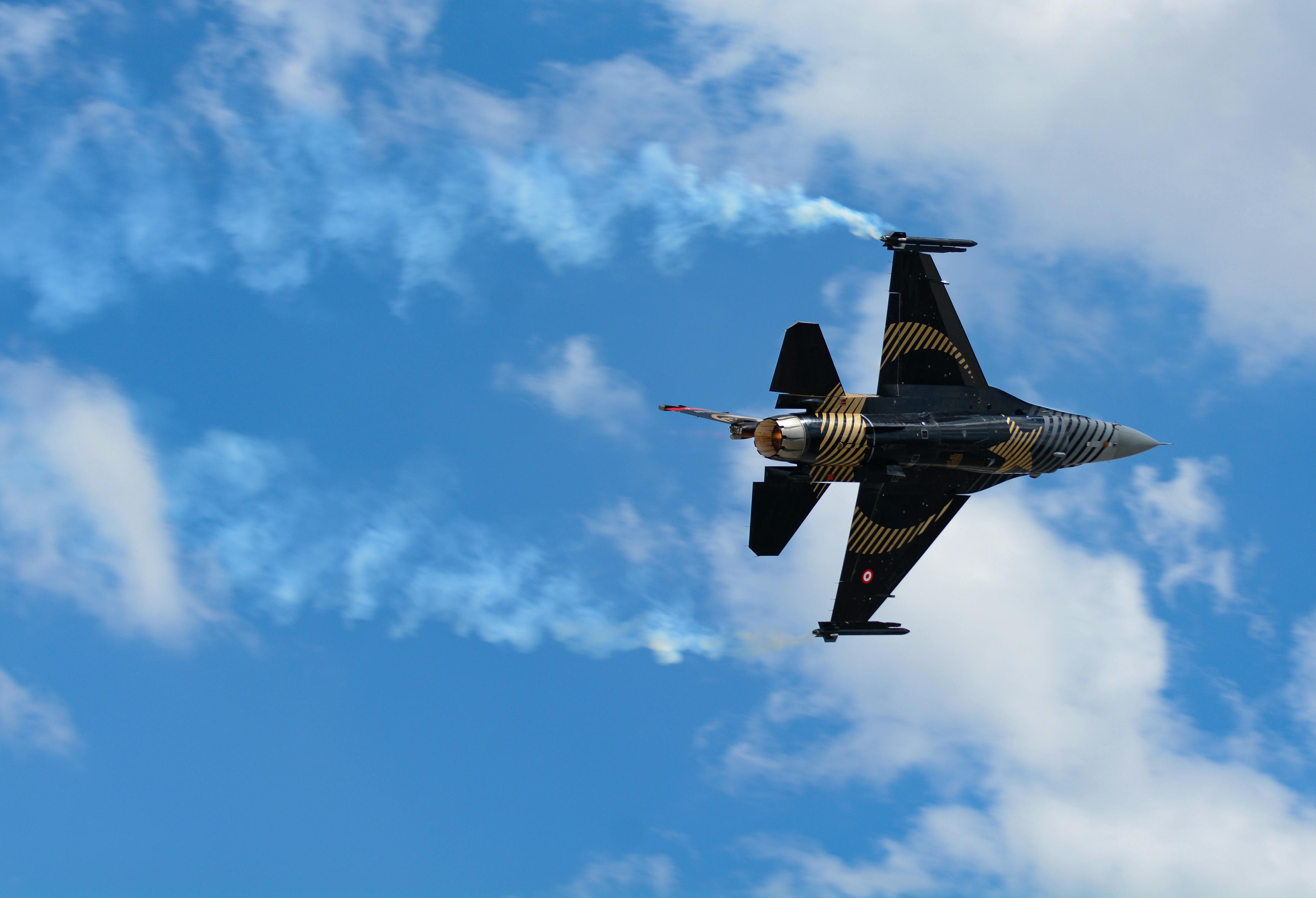 Dynamic display of a military fighter jet executing aerobatic maneuvers in a vibrant blue sky.