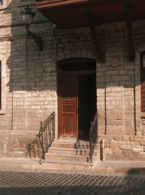 Free A rustic wooden door with stone facade on a sunny cobblestone street. Stock Photo