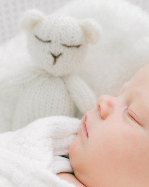 Closeup of a Baby Face Sleeping Next to a Yarn Teddy Bear