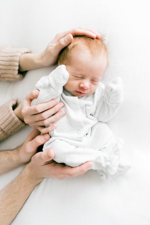 Mother and Father Hands Holding Sleeping Baby