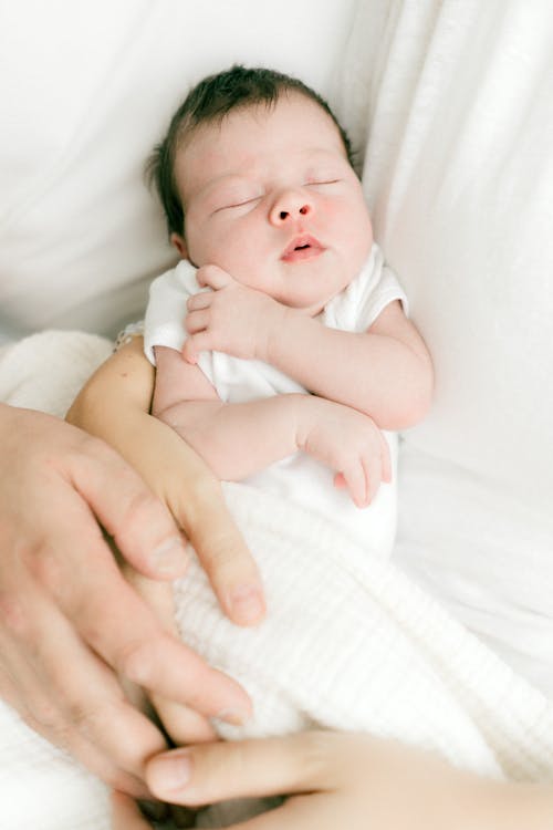 Tiny Newborn Sleeping in Parents Arms