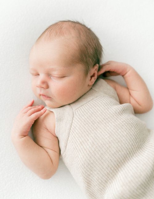 Free A serene portrait of a newborn baby asleep in a comfy romper, embodying innocence. Stock Photo