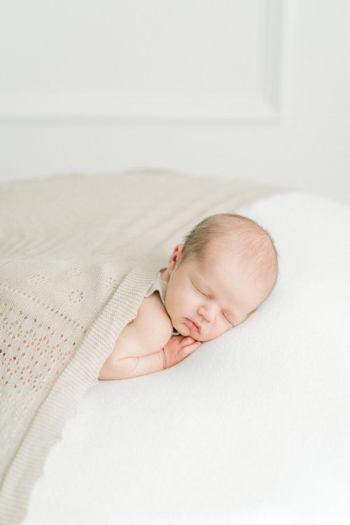 Free Serene image of a newborn baby sleeping softly under a light blanket. Stock Photo