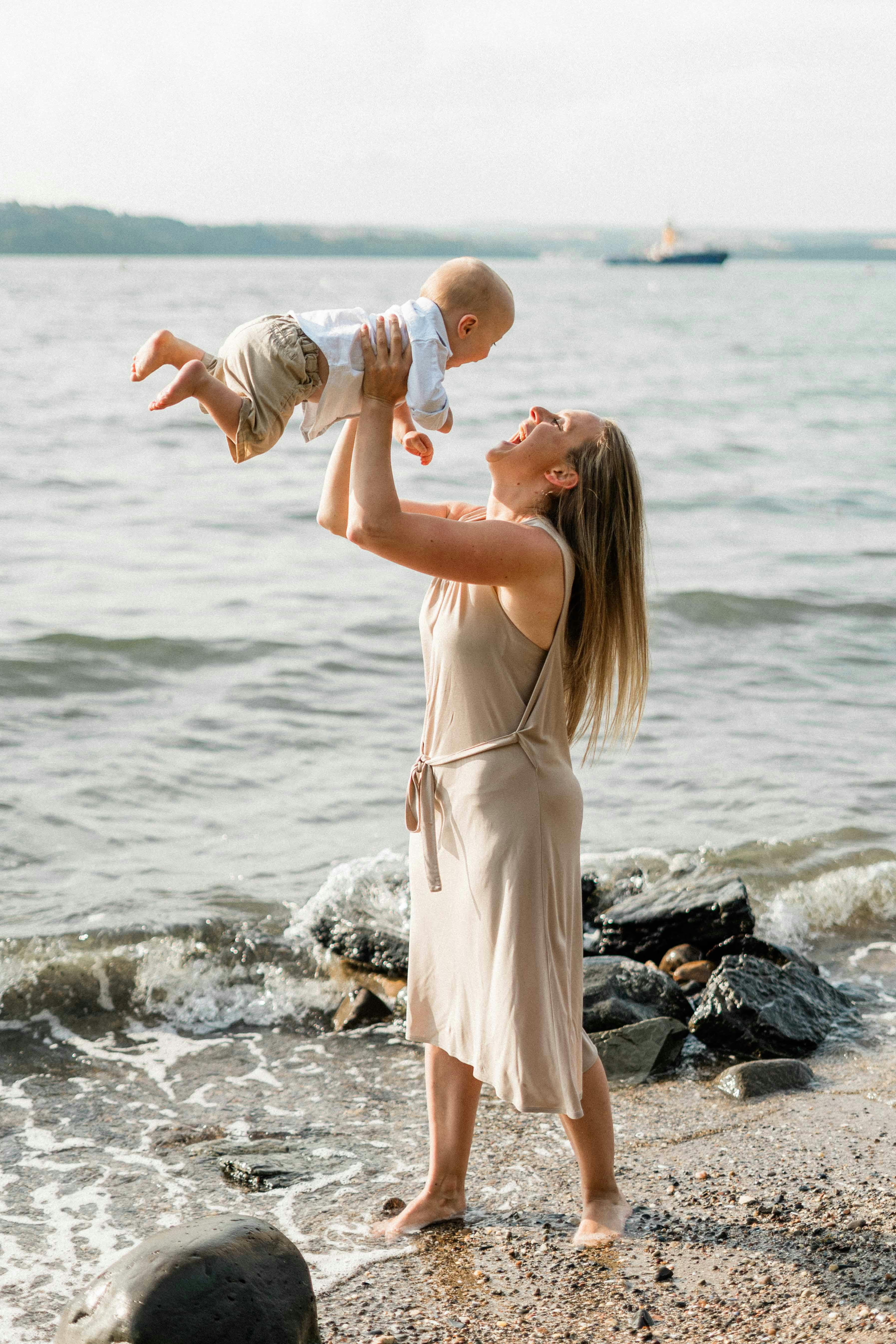 在海滩上，快乐的母亲抱着她的孩子，享受阳光明媚的一天