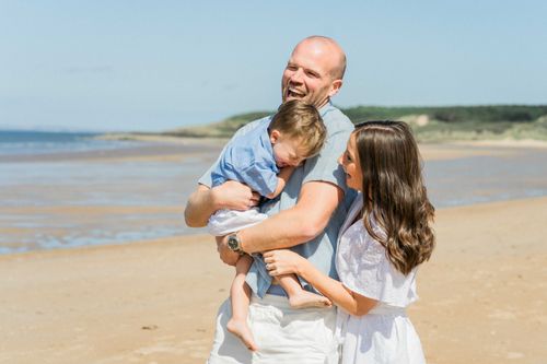 Free Joyful family enjoying a sunny day at the beach, sharing laughter and love. Stock Photo