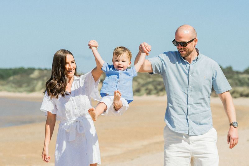Happy family with young child playing together on a sunny Mediterranean beach