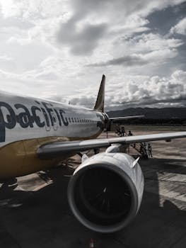 A commercial airplane is parked on an airport runway under a cloudy sky, showcasing air travel scenery.