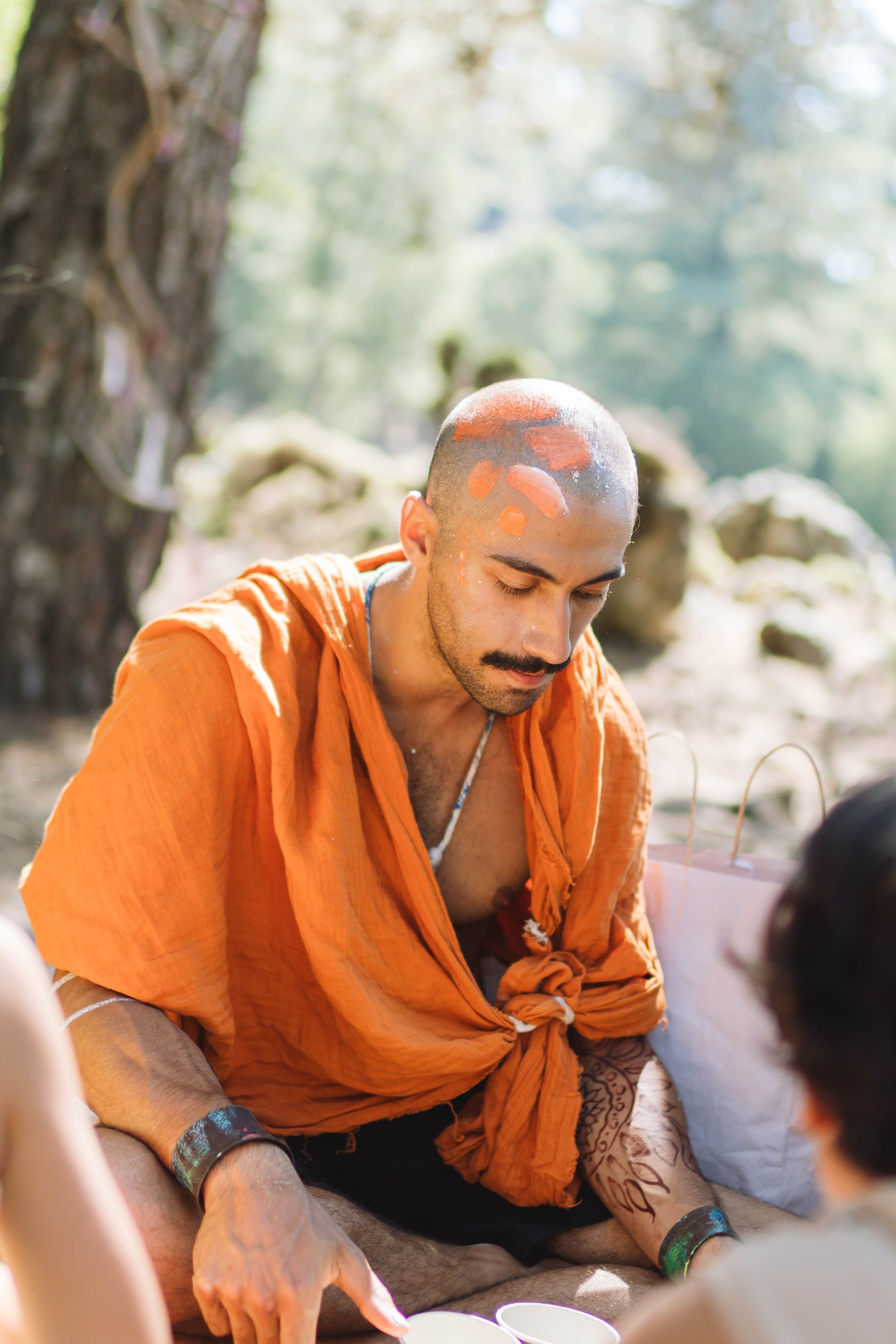 A serene Buddhist monk in traditional orange robes meditates outdoors, capturing a peaceful spiritual moment.
