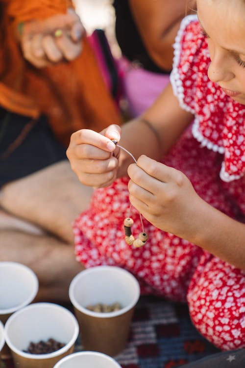 Girl Sitting and Making Bracelet