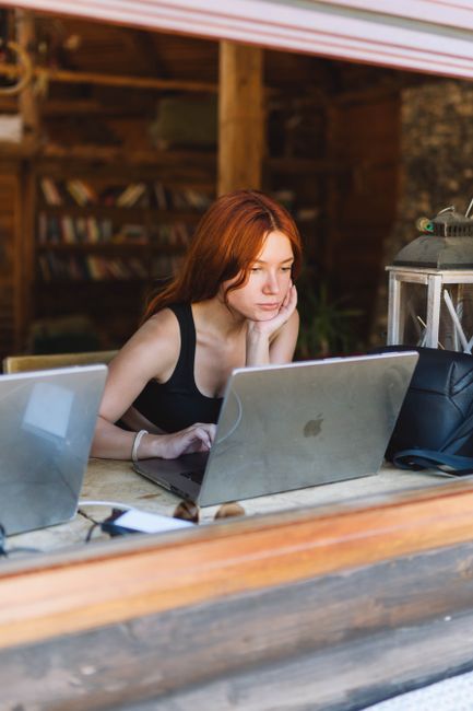 A focused woman with long hair works on a laptop in an indoor rustic setting, enhancing the cozy atmosphere.