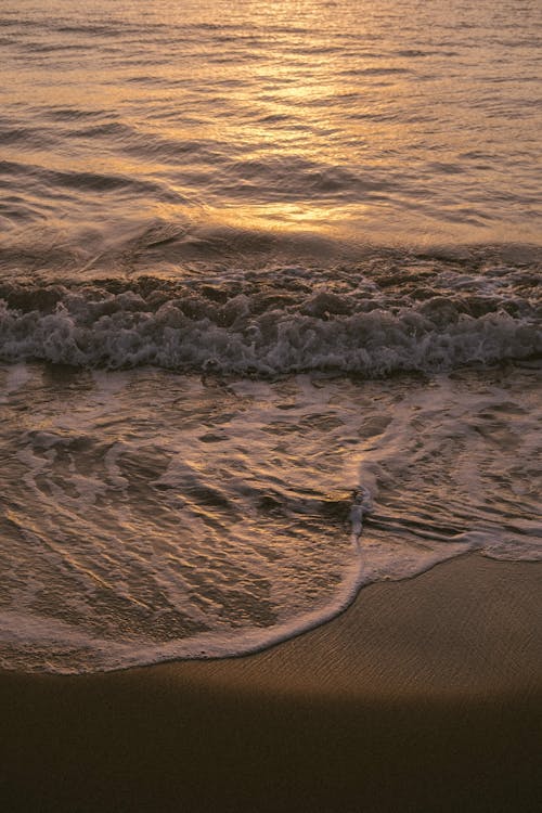 Close-up of Foamy Waves Washing Up the Beach at Sunset