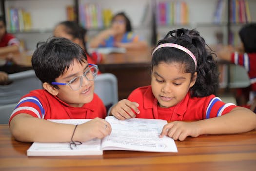 Two young children reading together in a bright classroom in Gurugram, India.