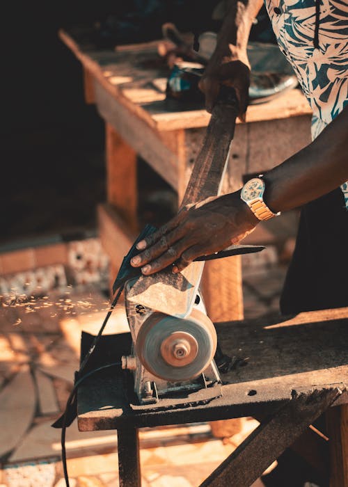 Man Using a Grinder to Make a Tool