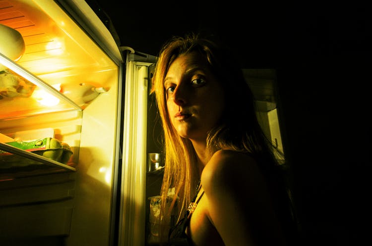 Portrait Of Woman By Open Fridge In Darkness