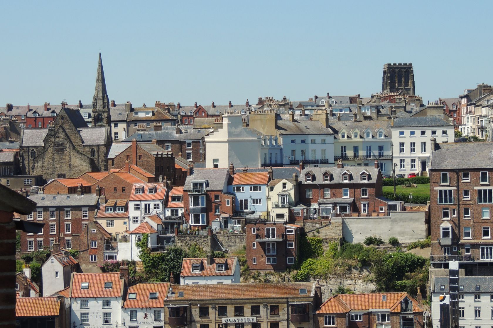 A picturesque view of a historic coastal town with iconic architecture under a clear blue sky.