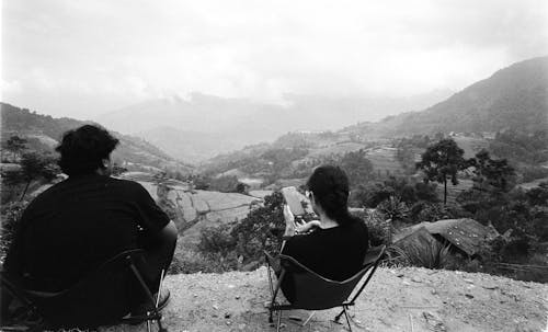 Woman and Man Sitting on Hilltop in Black and White