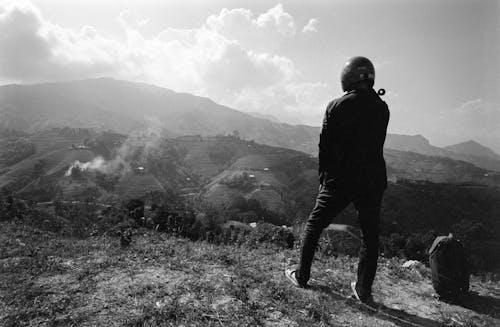 Man in Helmet Standing on Hill in Black and White