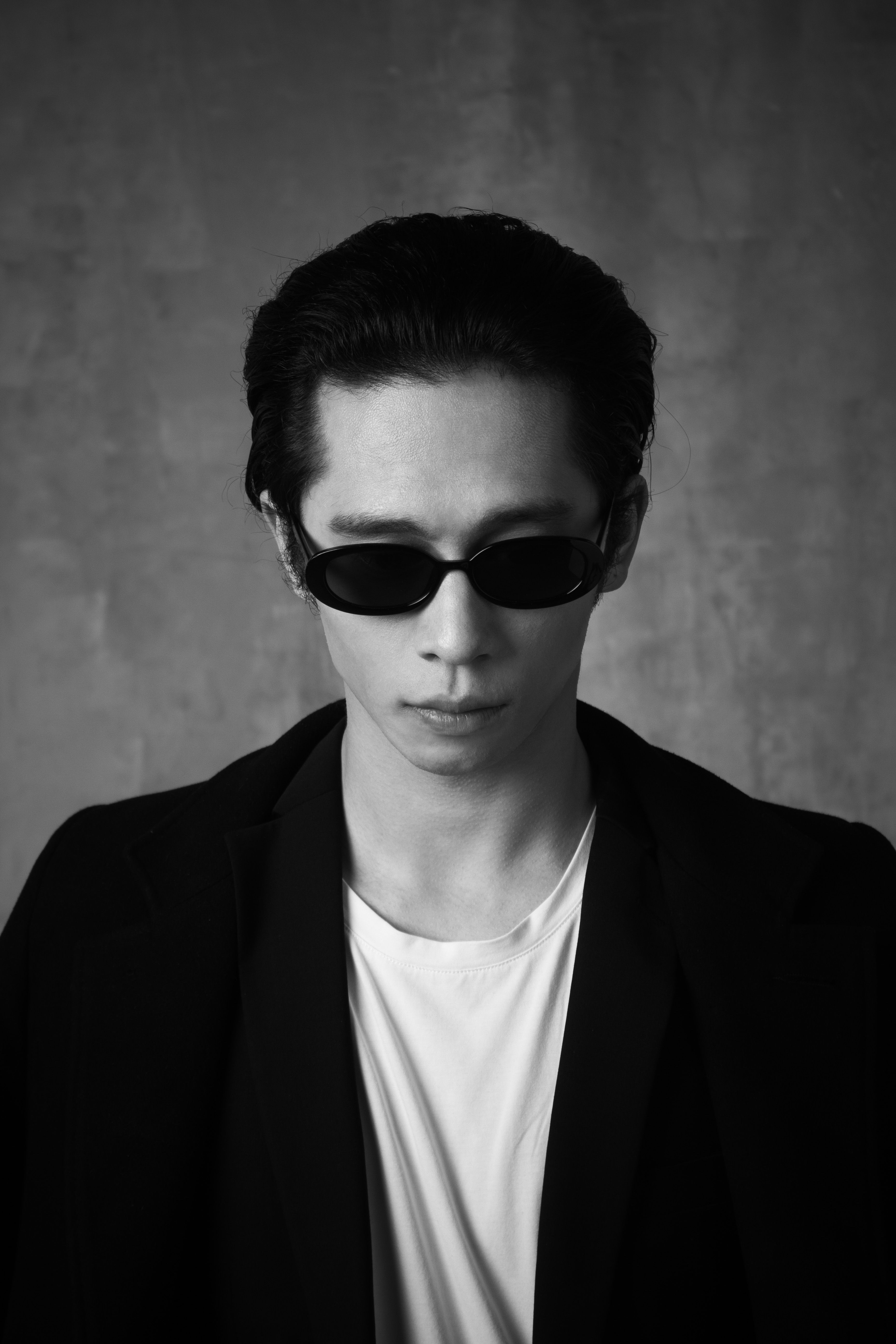 A striking black and white portrait of a man in sunglasses exuding modern fashion style.