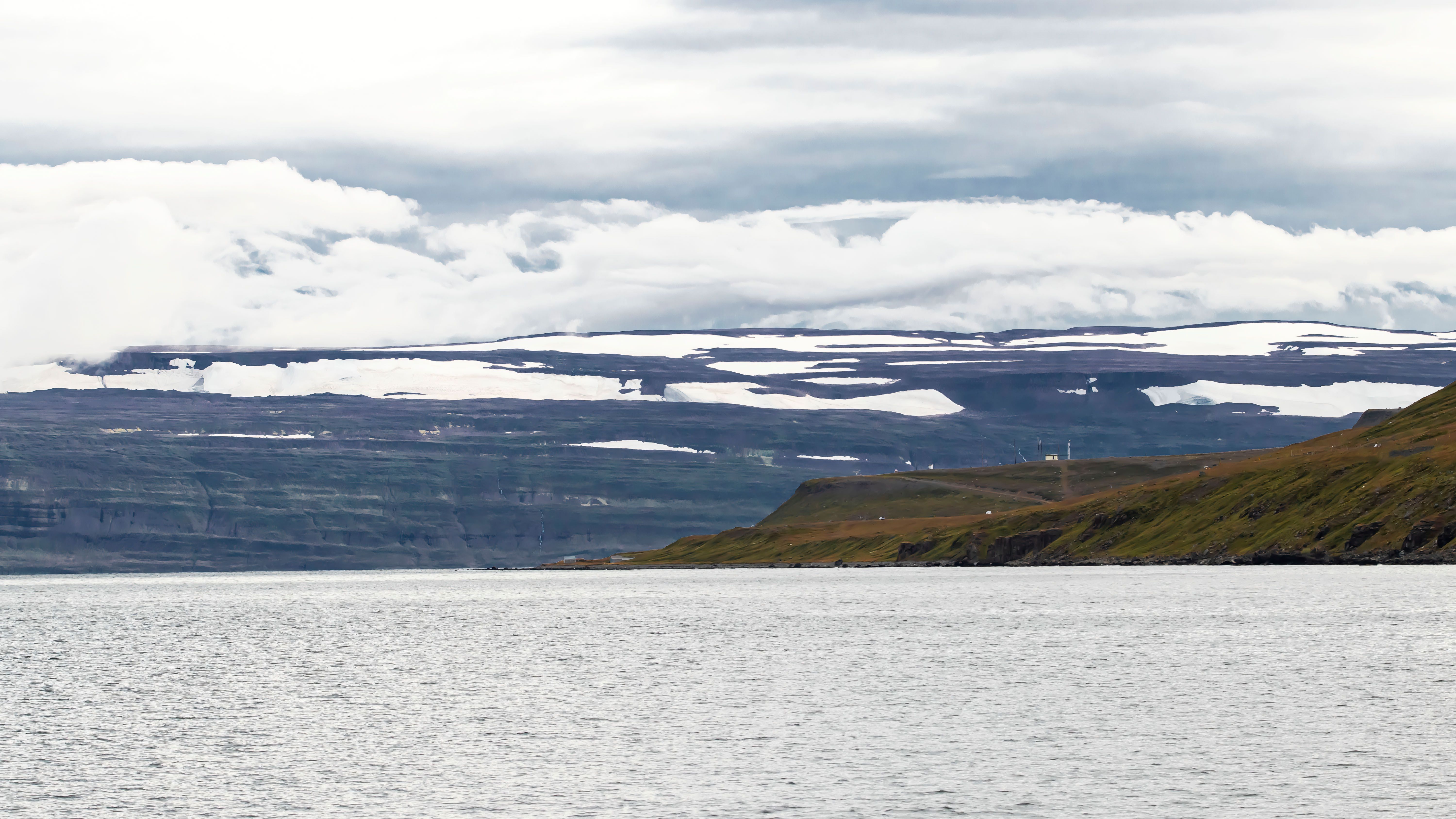 Panoramic view of the Westfjords in Iceland, showcasing mountains, sea, and a cloudy sky.