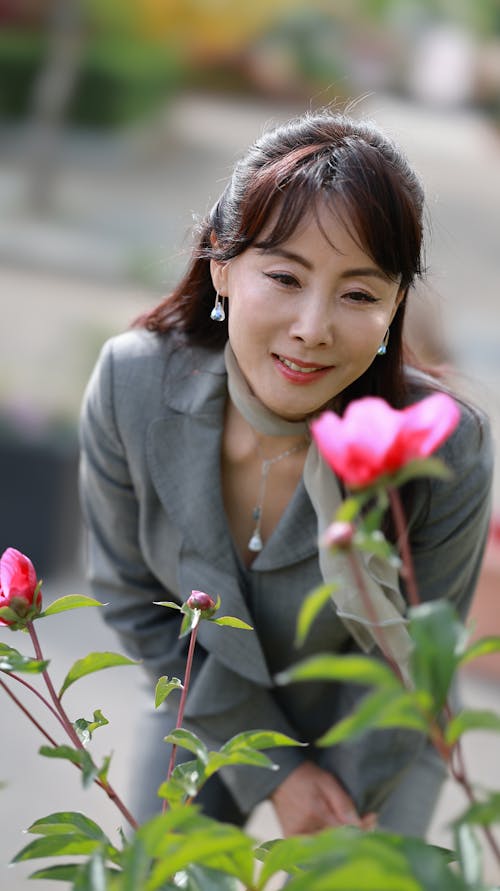 Smiling Woman Admiring a Blooming Flower