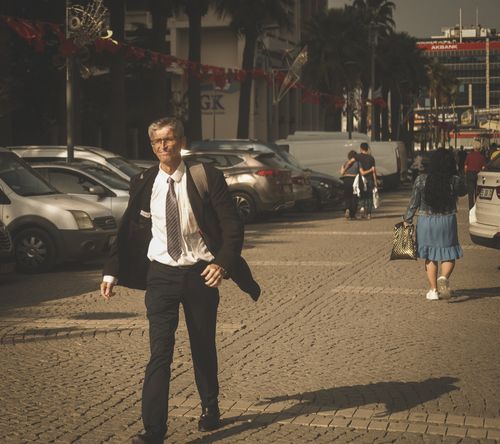 Free Senior man in suit confidently walks down a sunny city street. Stock Photo