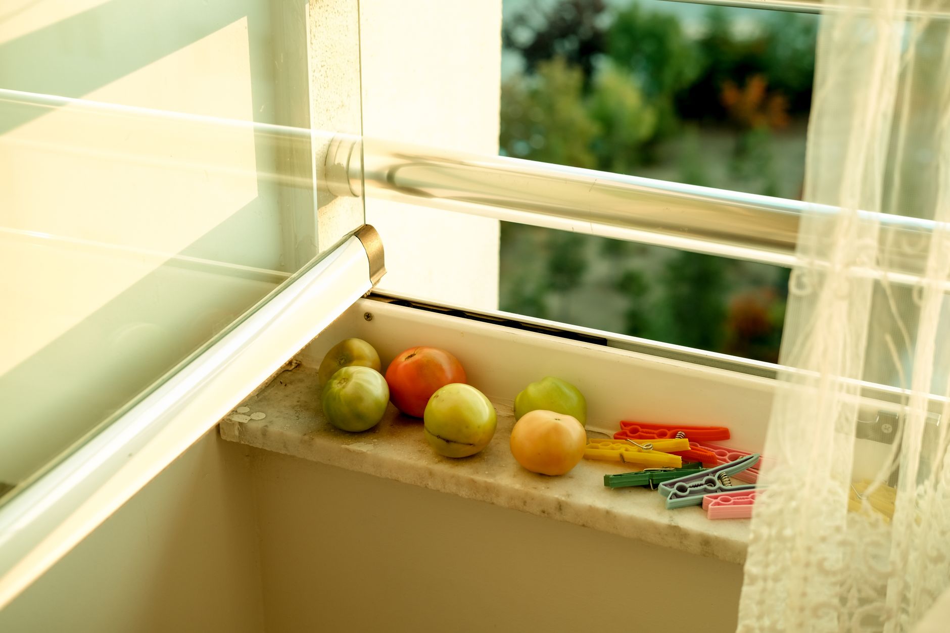 Fresh apples and clothespins on a sunlit windowsill creating a warm, inviting scene.