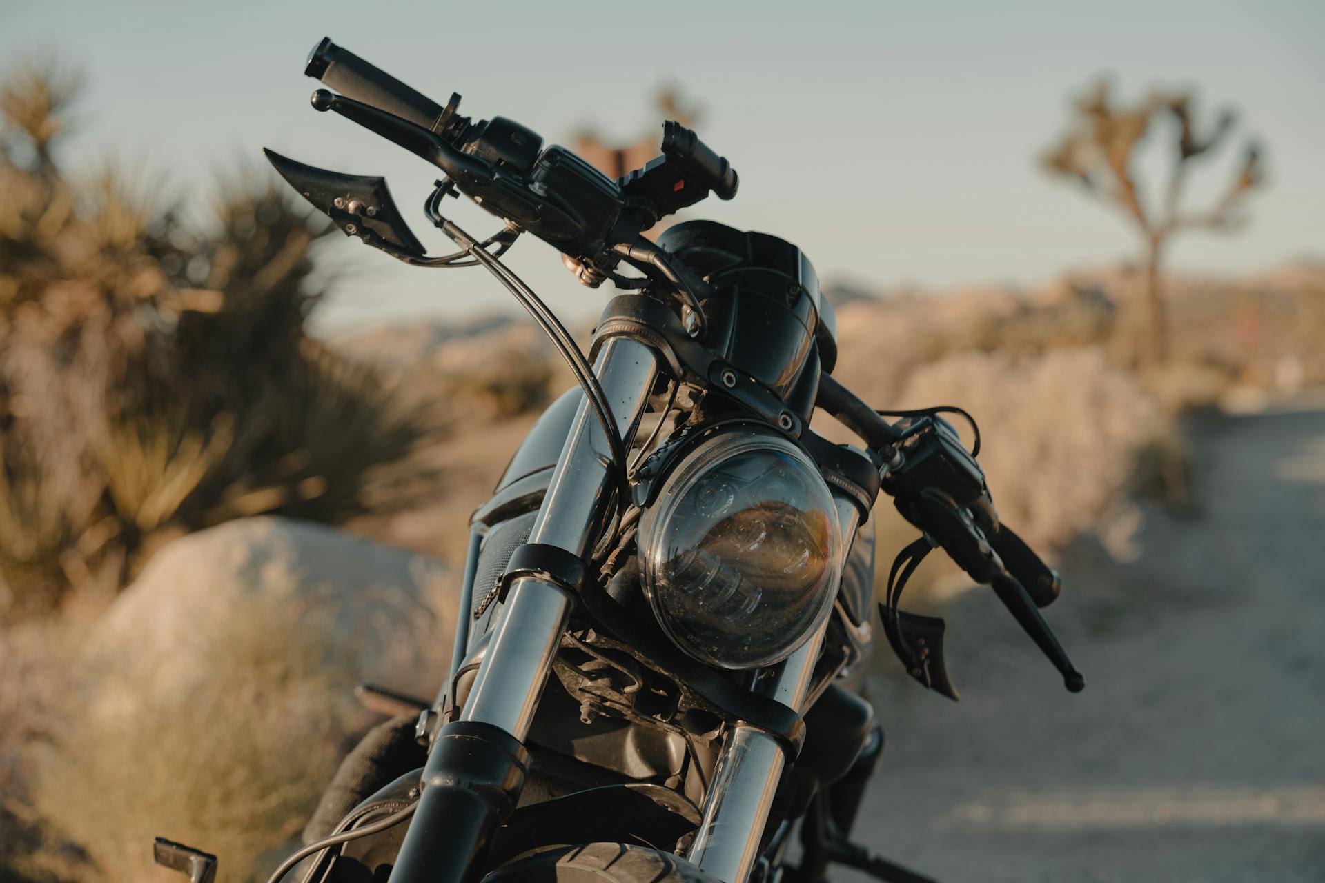 Motorcycle parked on a dirt road in Joshua Tree, California during golden hour.