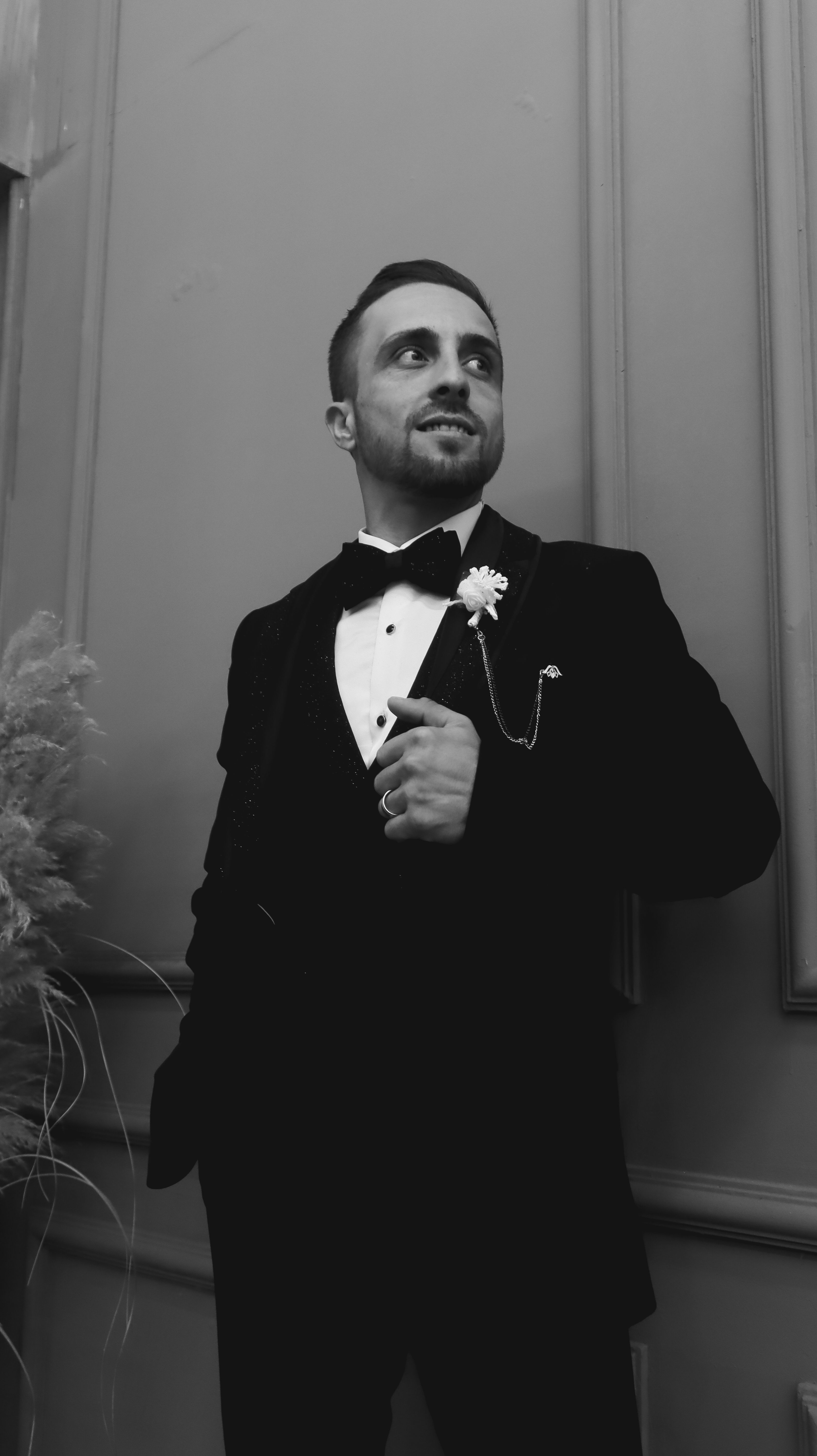 Elegant black and white portrait of a smiling groom in a classic suit, exuding sophistication.