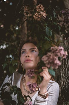 在自然界中，女人与项链被花和树包围，看起来令人愉快