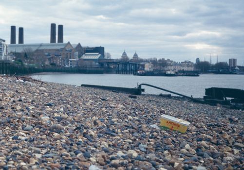 A beach with a trash can on it and a building in the background