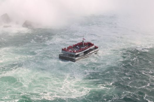 Aerial view of a ferry navigating the misty waters near Niagara Falls.