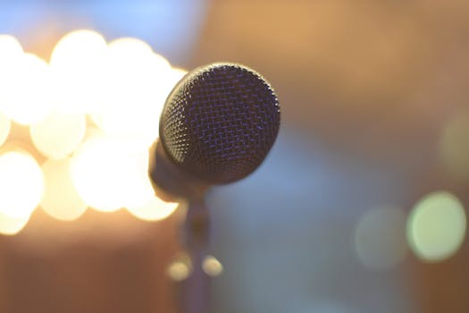 A close-up of a microphone with soft bokeh lighting in the background, creating a warm ambiance.