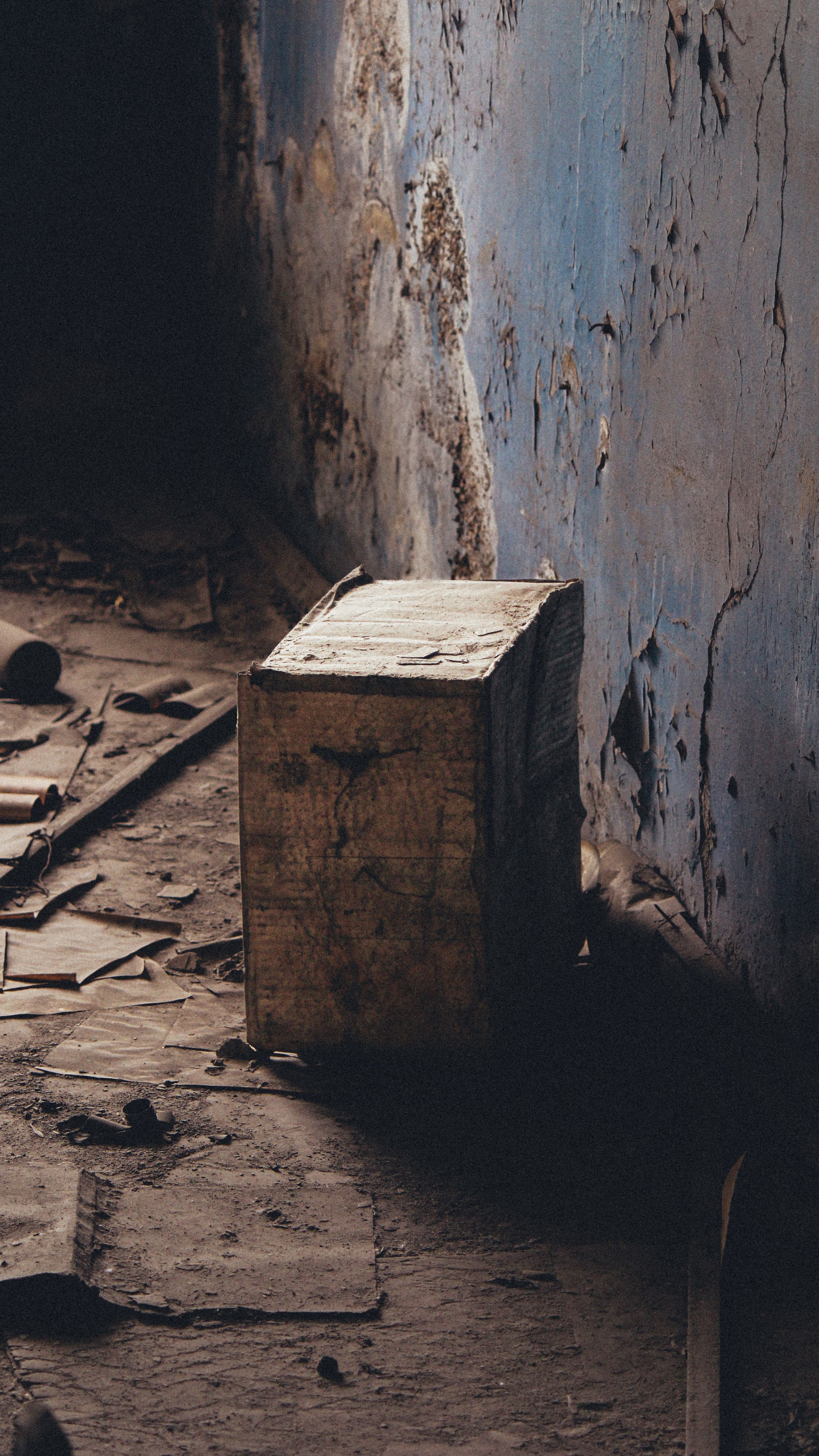 A weathered box in an abandoned room with cracked walls, urban decay setting in Baku.