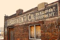 Rustic brick building exterior with an aged sign and window, capturing urban decay.