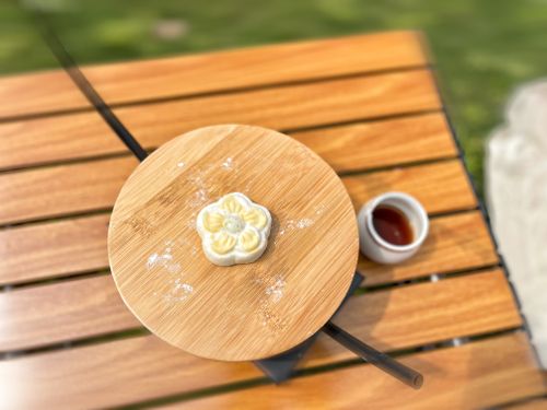 Free Close-up of a flower-shaped mooncake on a wooden tray with tea outdoors in Shanghai. Stock Photo