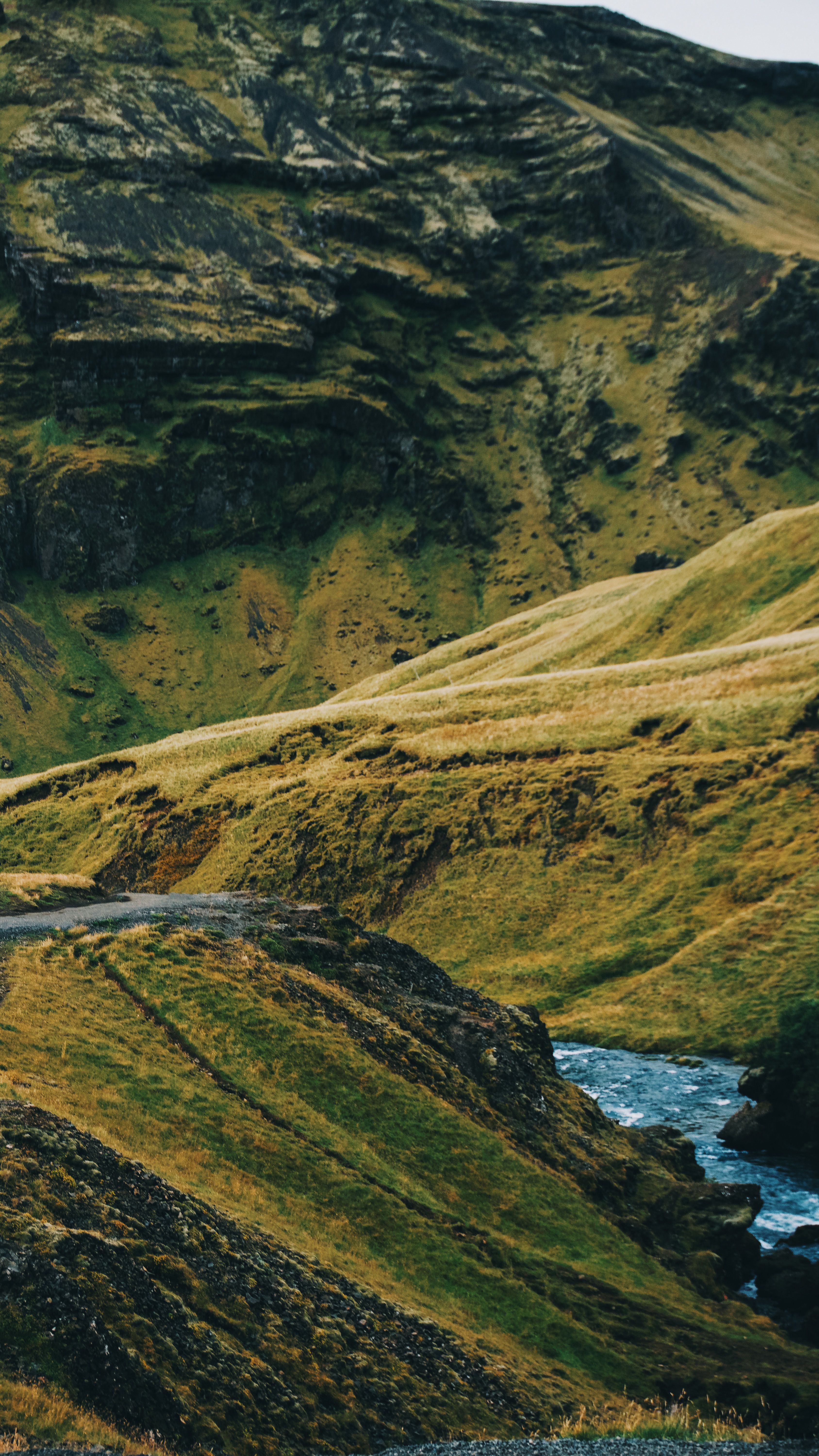 Breathtaking view of lush green hills and a clear river flowing through a mountainous region.