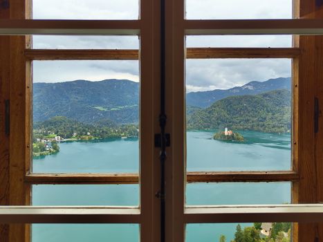 Beautiful view of Lake Bled and its island through a wooden-framed window.