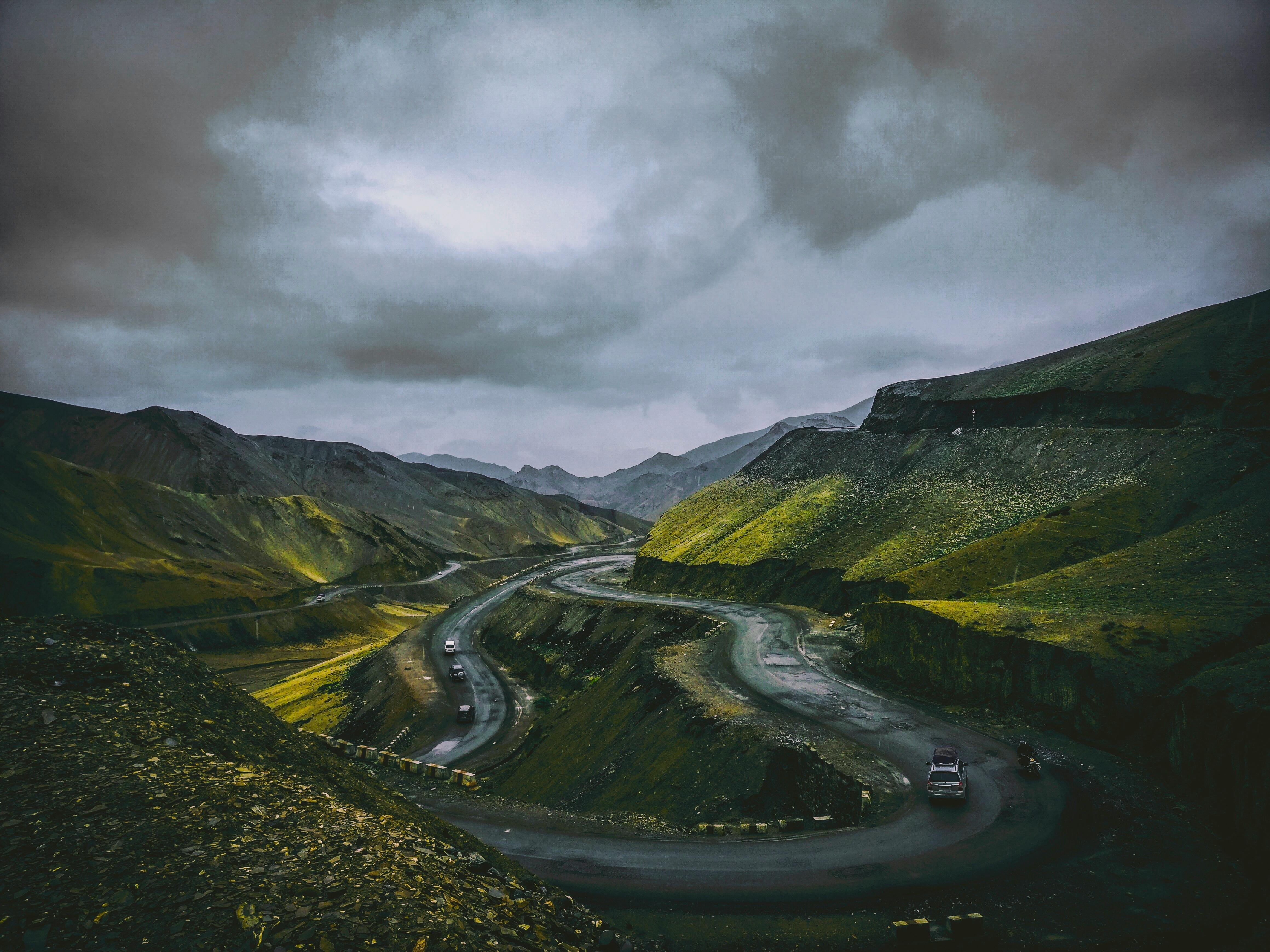 一条蜿蜒的道路，穿行于山势险峻的景观之中，头顶乌云密布