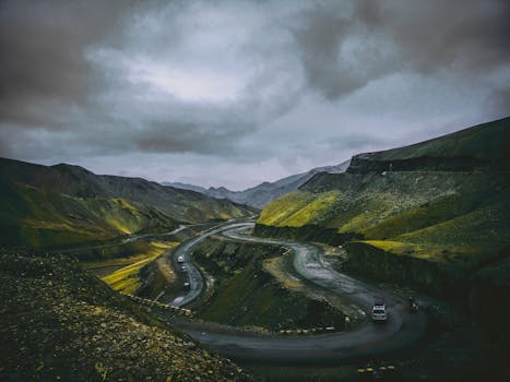 一条蜿蜒的道路，穿行于山势险峻的景观之中，头顶乌云密布